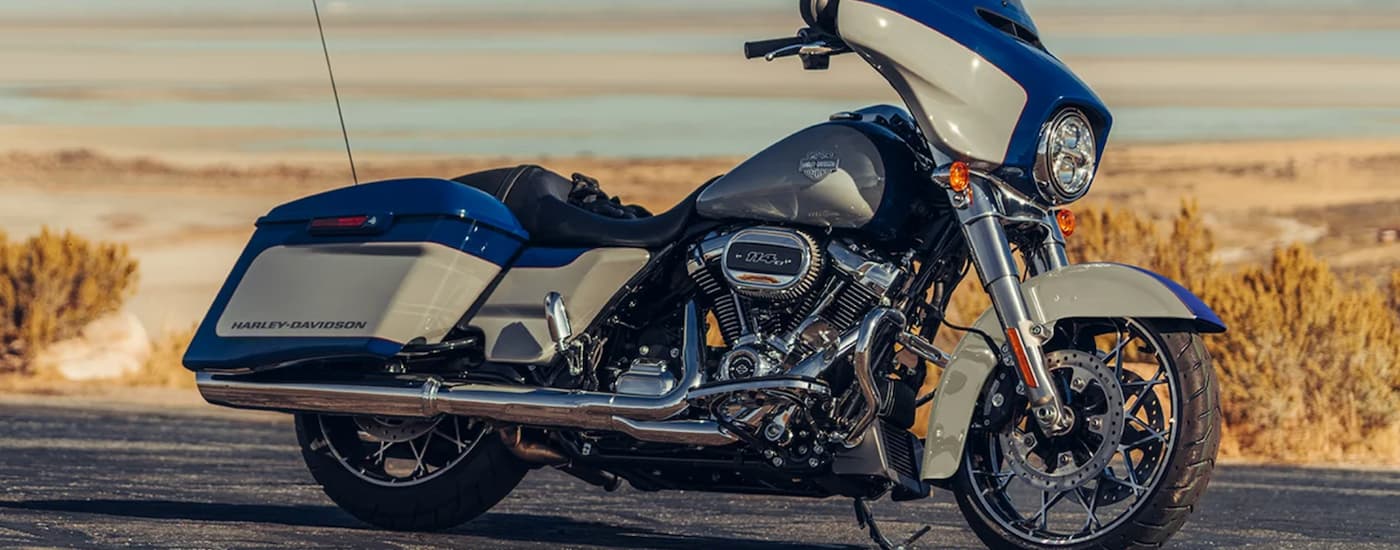 A blue and white 2023 Harley-Davidson Street Glide is shown from the side parked in a desert.
