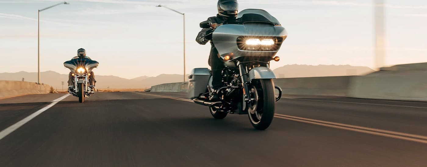 Two grey 2023 Harley-Davidson Road Glide Specials are shown driving on an open desert highway.
