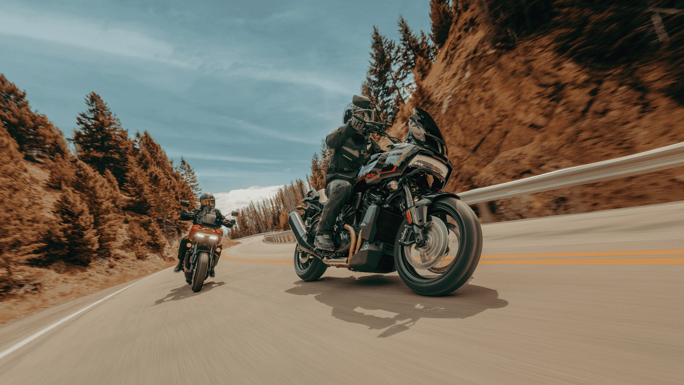 Two riders lean into curves on Harley-Davidson® Adventure Touring bikes, exploring scenic mountain roads.