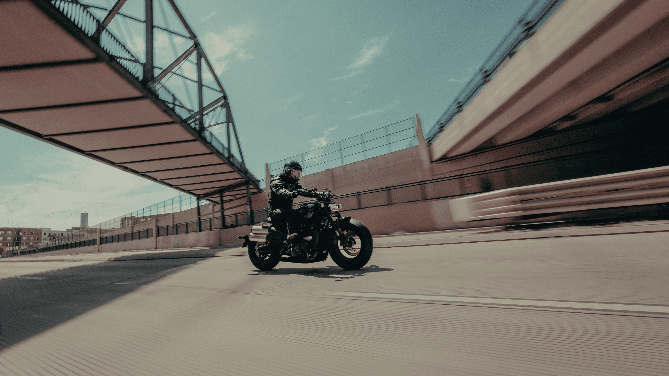 A rider speeds beneath an overpass on a Harley-Davidson® Sport motorcycle, navigating urban streets.