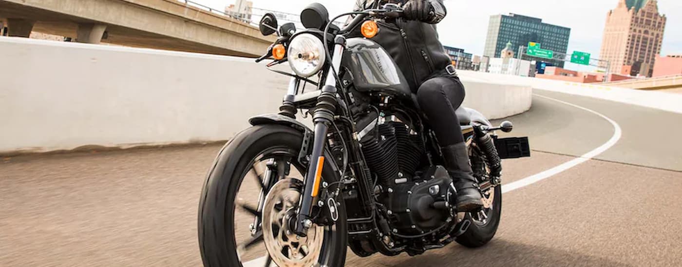 A person is shown riding a grey 2022 Harley-Davidson Iron 883 on a highway exit.