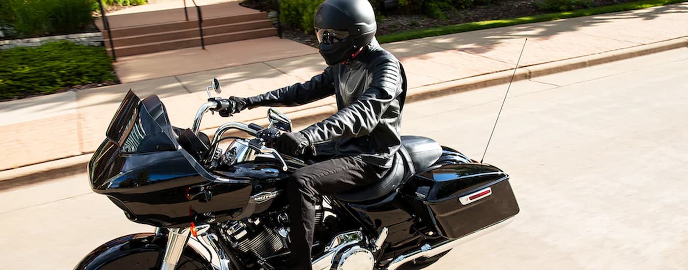 A black 2022 Harley-Davidson Road Glide is shown being ridden on a city street.