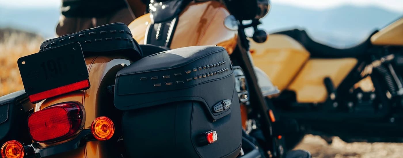A close up of black saddlebags are shown on an orange 2023 Harley-Davidson Heritage Classic.