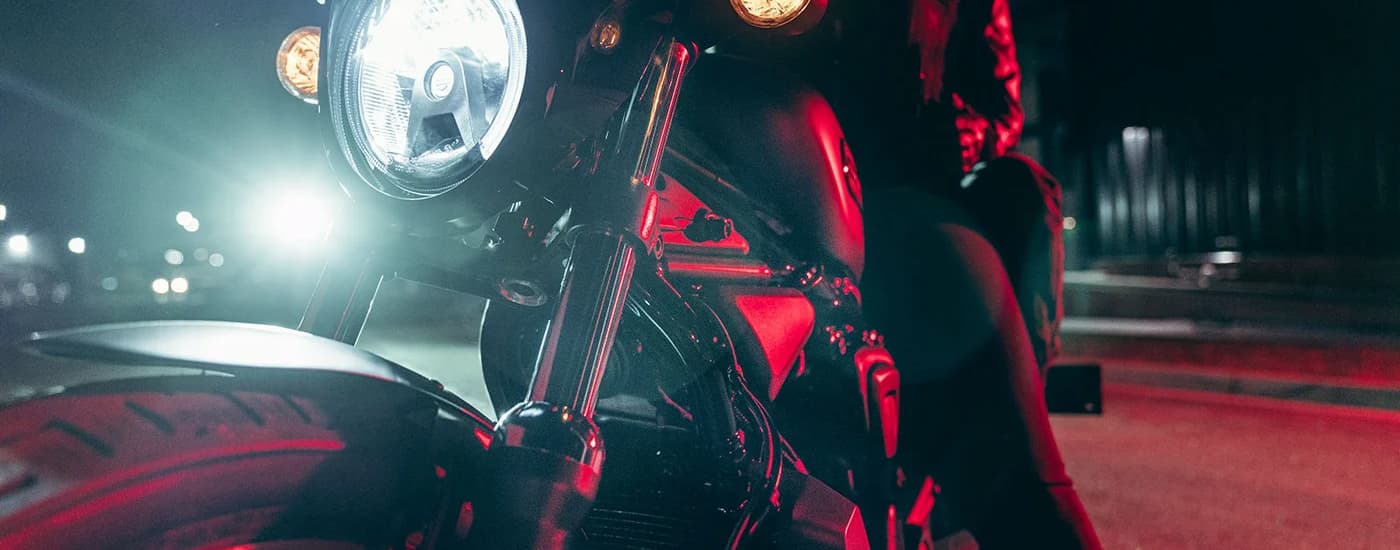 A close up of a black 2023 Harley-Davidson Nightster Special at night shows the front headlight …