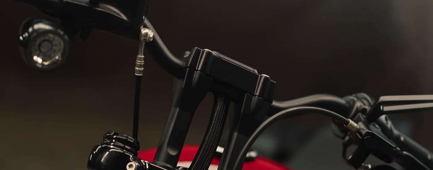 A close up of the handlebars on a red 2023 Harley-Davidson Street Bob 114 is shown. 