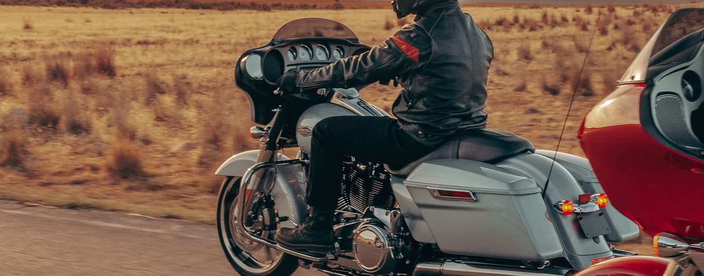 A grey and a red 2023 Harley-Davidson Street Glide are shown riding on an open desert road.