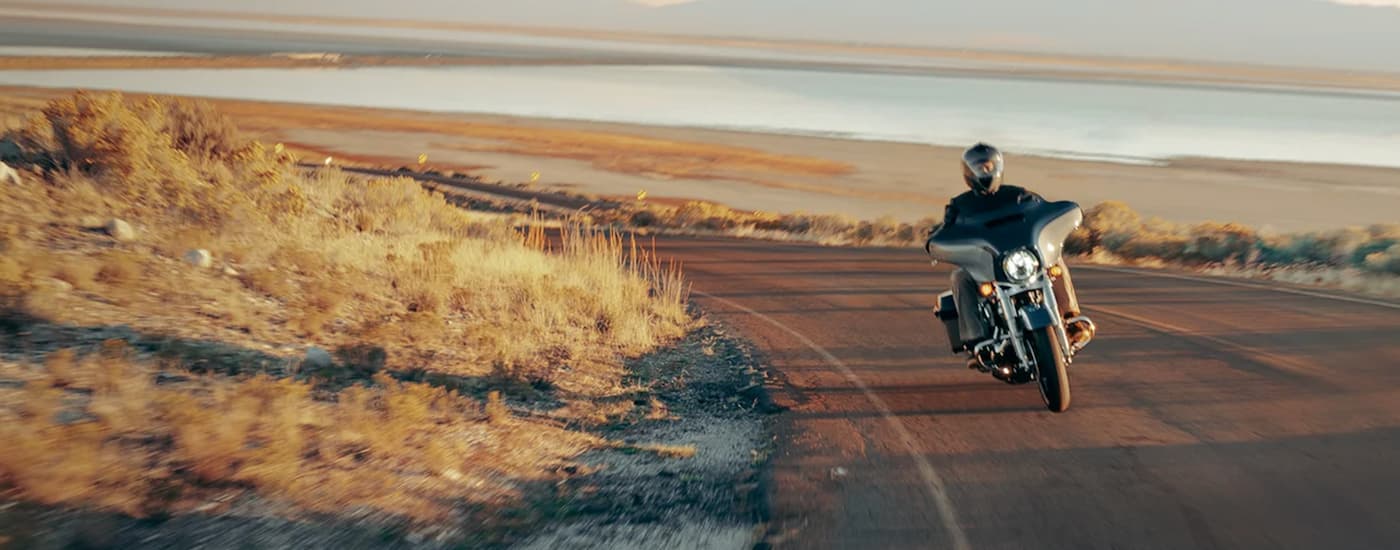 A blue and white 2023 Harley-Davidson Street Glide is shown from the front while driving down an …