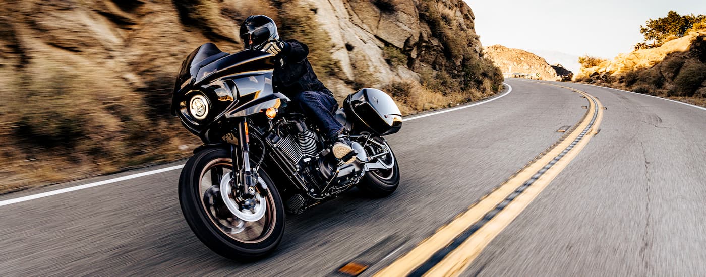 A black 2021 Certified Pre-Owned Harley-Davidson Low Rider ST is shown rounding a corner.