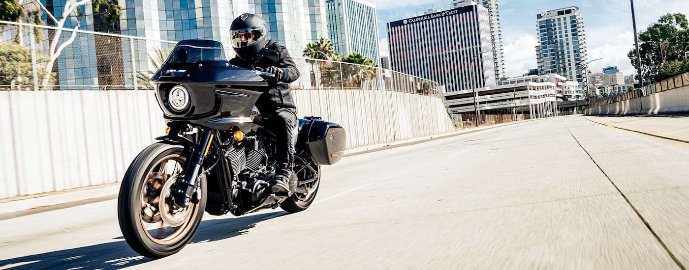 A black 2022 Harley-Davidson Low Rider ST is shown driving on a city street after looking at a …