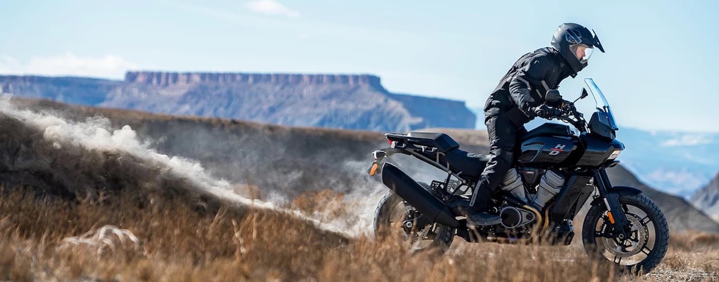 A black 2022 Harley-Davidson Pan America 1250 is shown from the side kicking up dust.