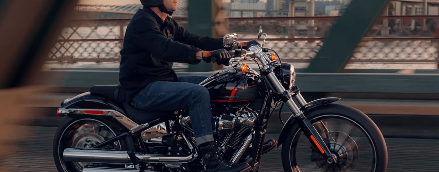 A man is shown driving a 2024 Harley-Davidson Breakout on a city bridge.