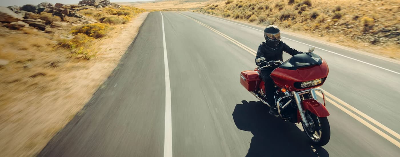 A red 2023 Harley-Davidson Road Glide for sale is shown riding on an open highway.