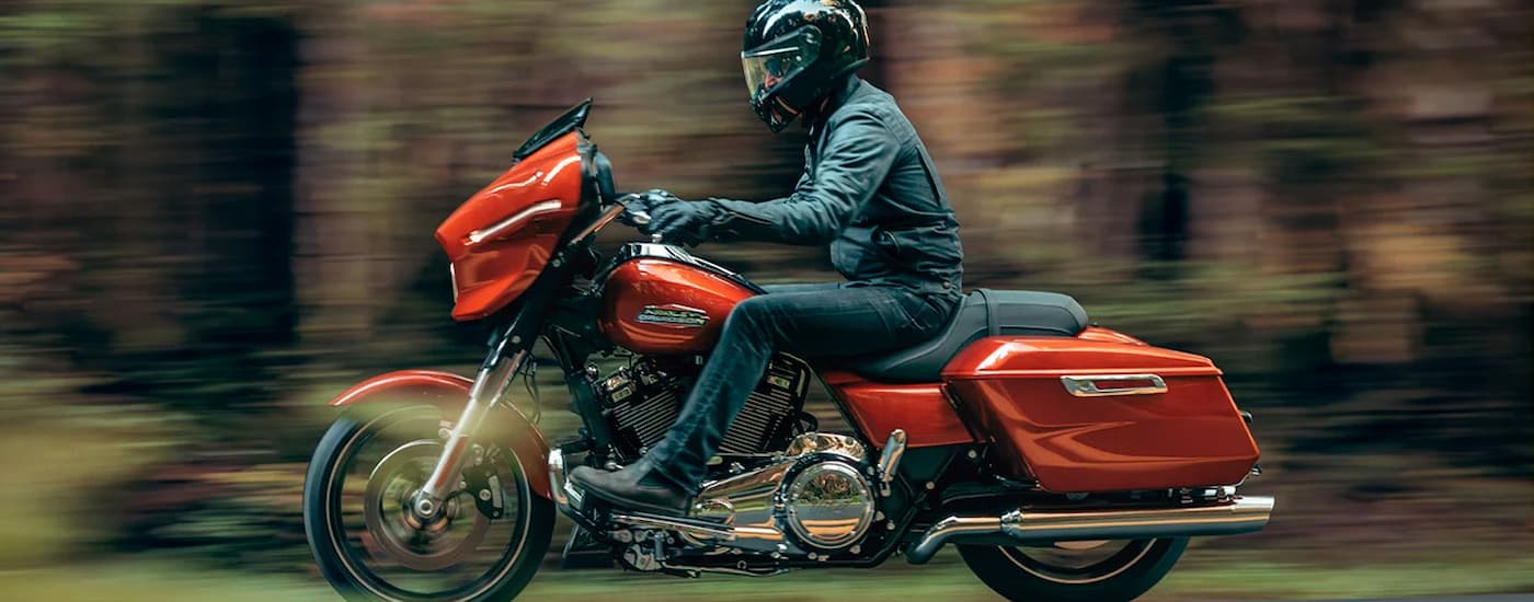 An orange 2024 Harley-Davidson Street Glide is driving on an open road after visiting Bellaire.