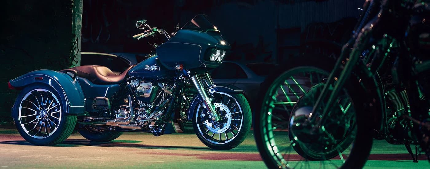 A blue 2023 Harley-Davidson Road Glide 3 is shown parked underneath a street light at night.