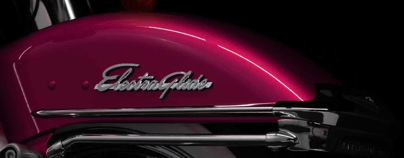 A close up shows the Electra Glide logo on a pink 2023 Harley-Davidson Electra Glide Highway King.