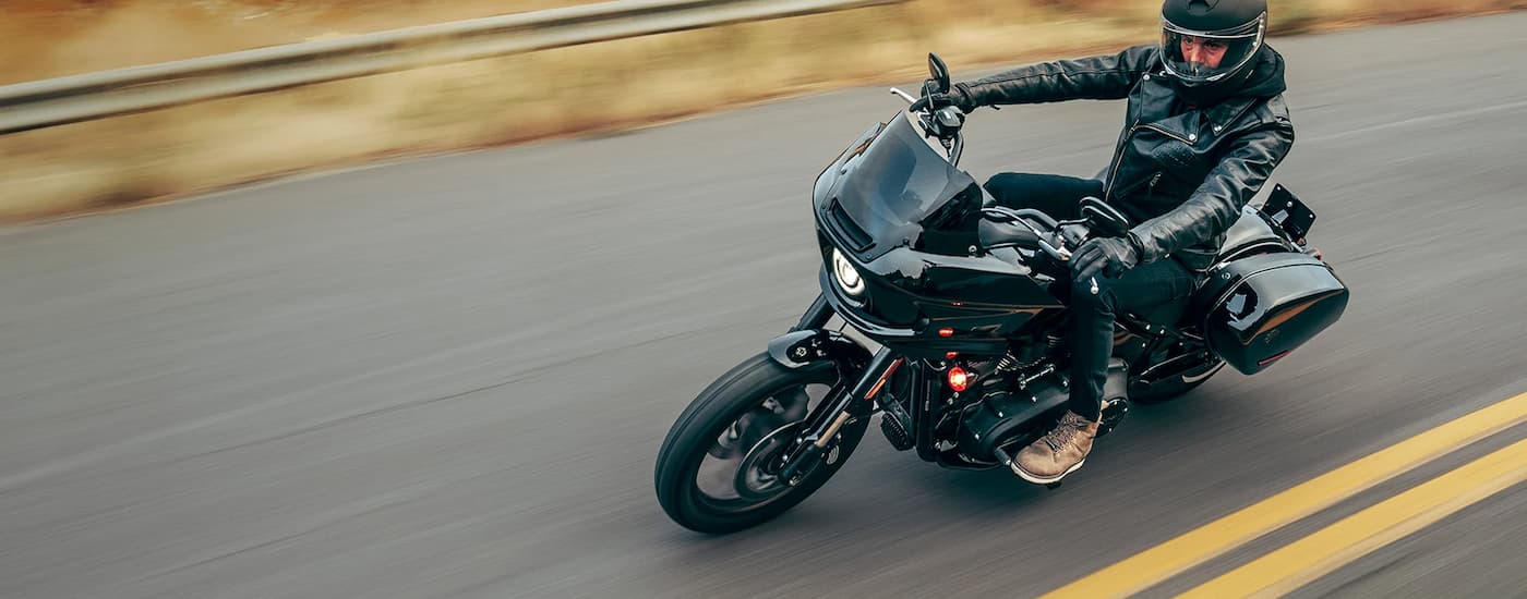 A black 2023 Harley-Davidson Low Rider ST is shown driving on an open road after leaving a …