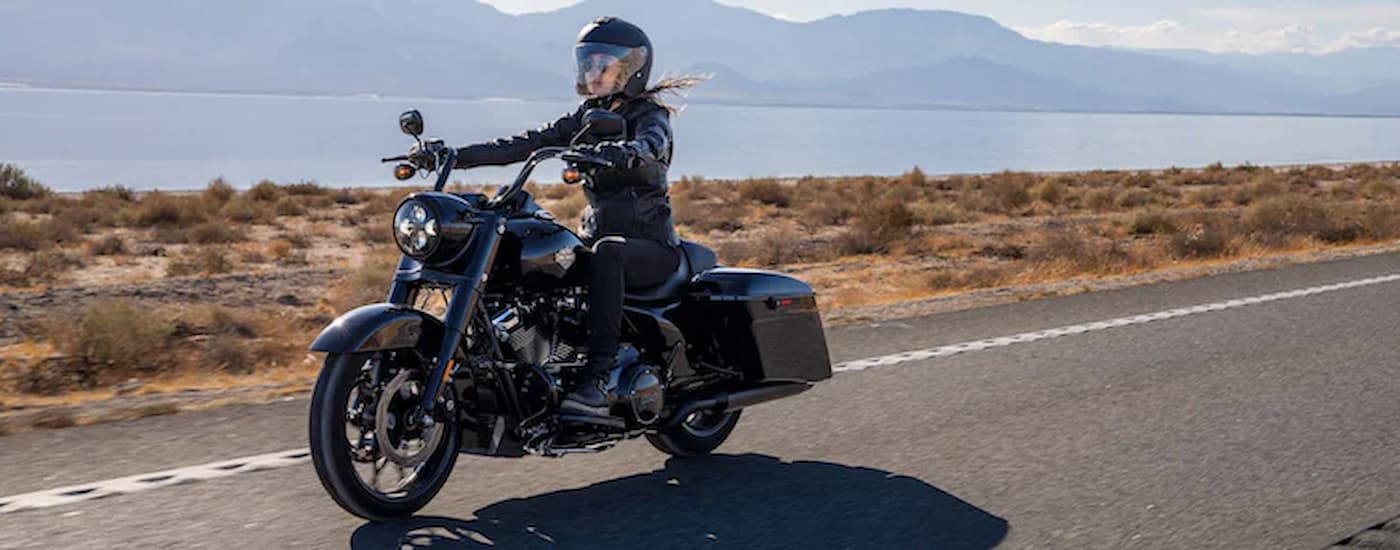 A black 2022 Harley-Davidson Road King Special is shown driving past a lake after leaving a Sugar …