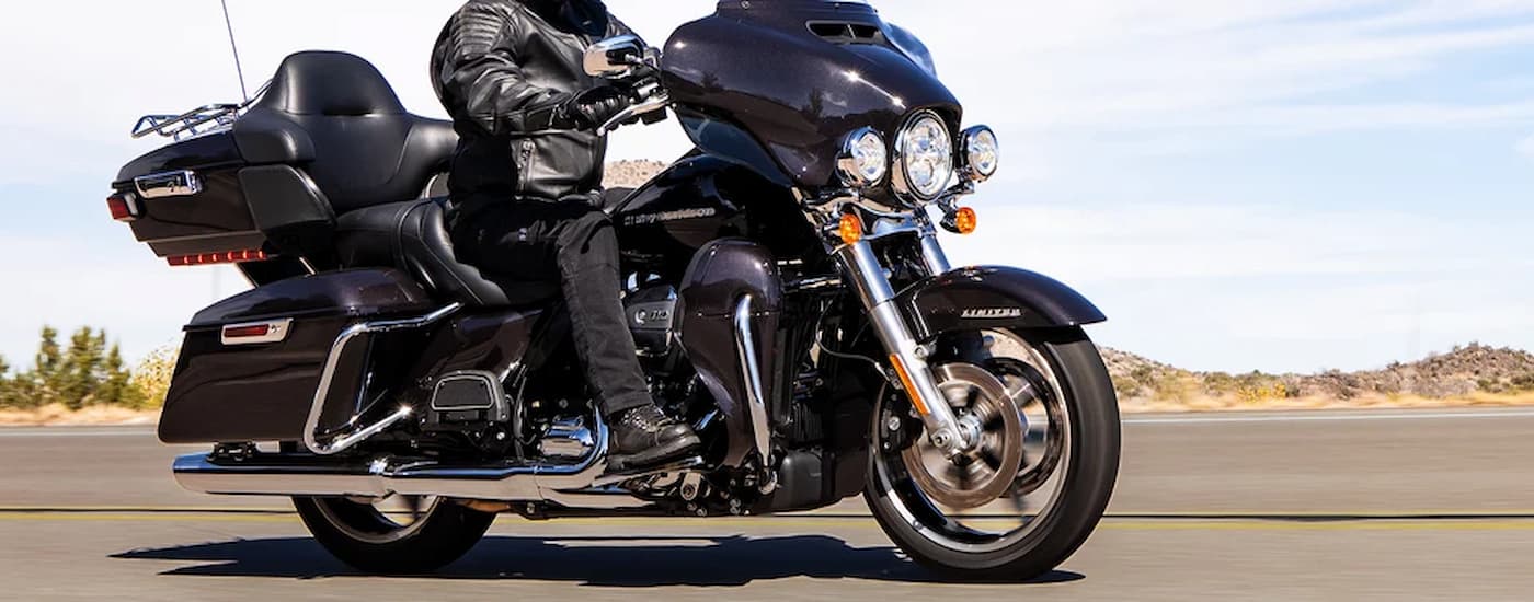 A black 2022 Harley-Davidson Ultra Limited is shown from the side driving on an open road.