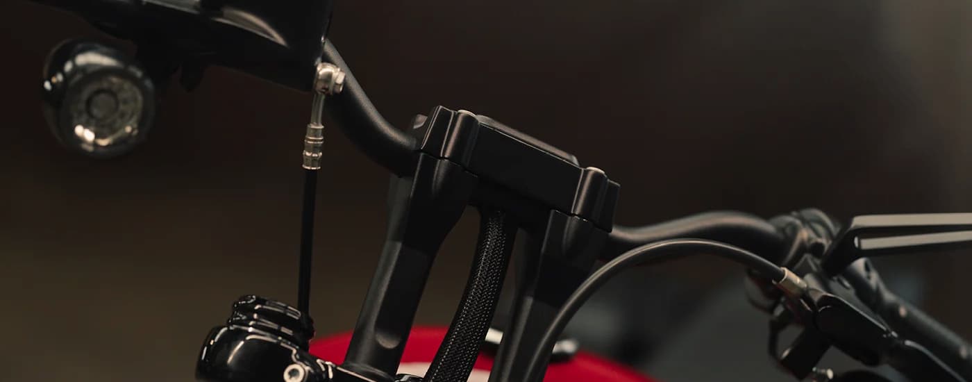 A close up of the handlebars on a red 2023 Harley-Davidson Street Bob 114 is shown.