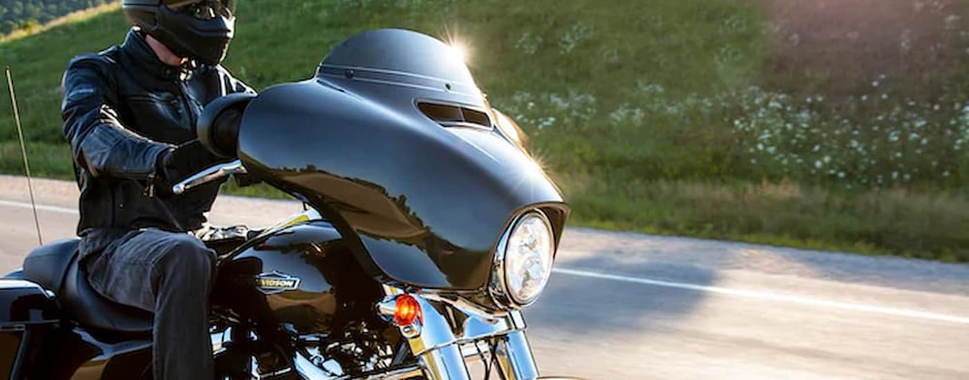 A black 2022 Harley-Davidson Street Glide is shown driving on a highway after leaving a used …