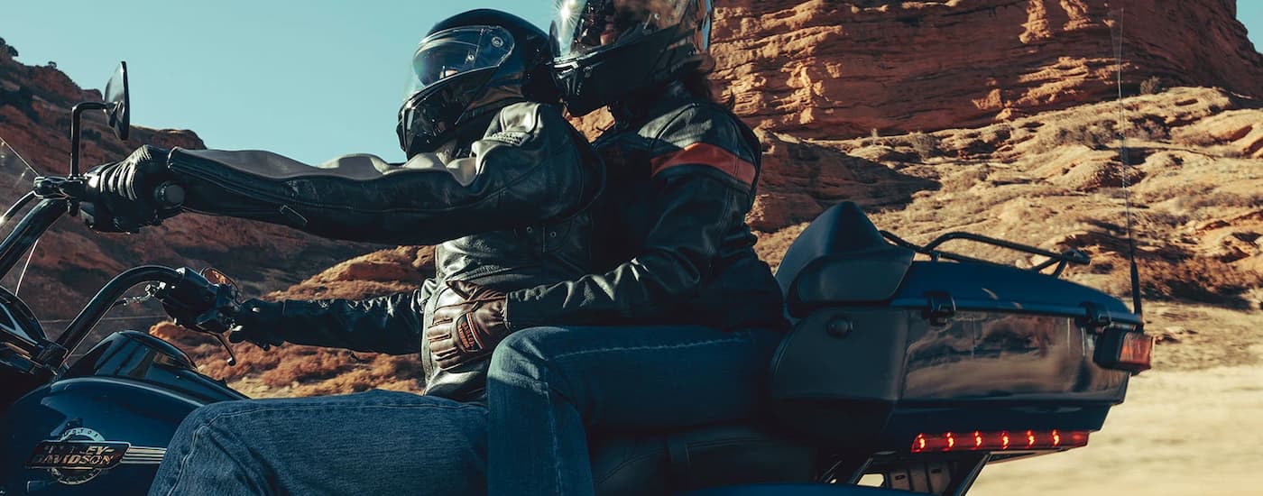 A couple is shown test riding a used 2022 Harley-Davison Road Glide Limited for sale on an open …